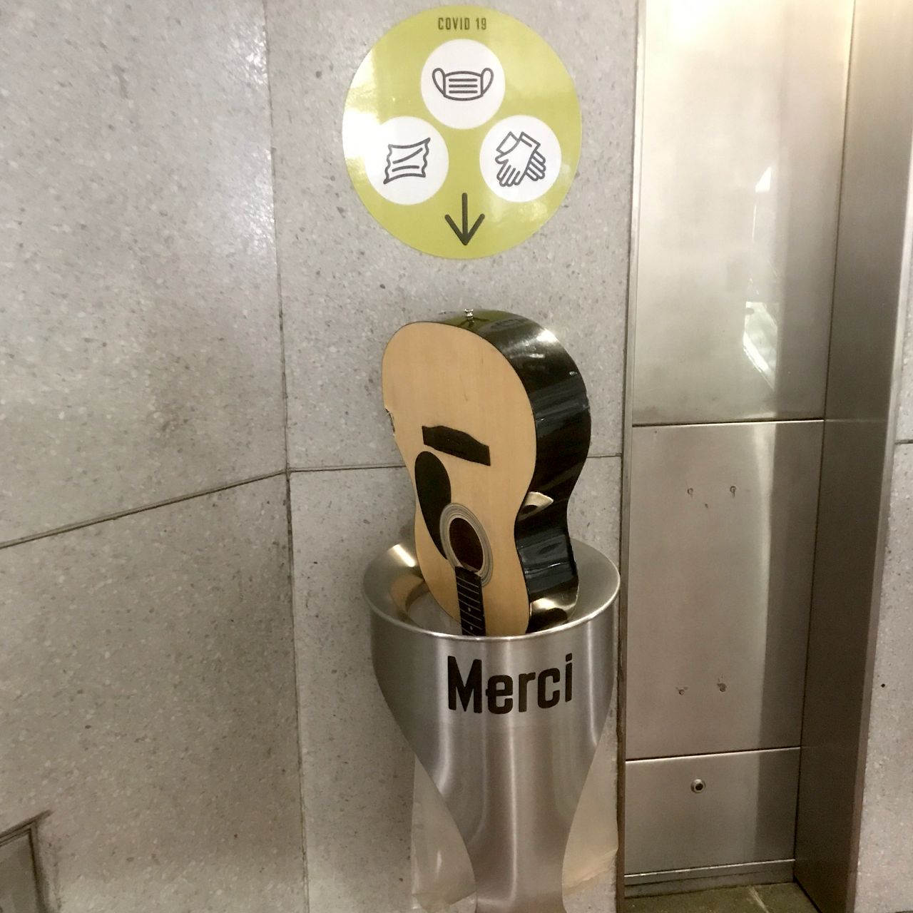 photo d'une guitare acoustique jetée dans une petite poubelle du métro à Paris.